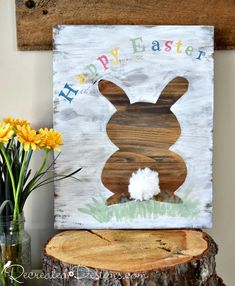 a wooden sign that says happy easter with a bunny on it and some flowers in the vase