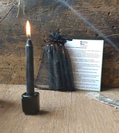 a lit candle sitting on top of a wooden table next to a piece of paper