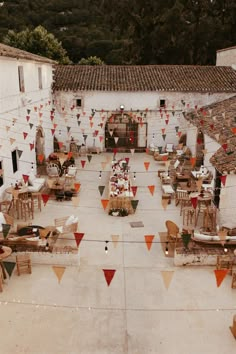 tables and chairs are set up outside for an outdoor party with flags hanging from the roof