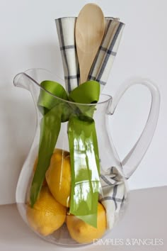 a glass pitcher filled with lemons and green ribbon