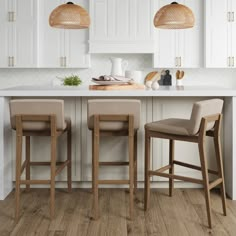 two stools in front of a kitchen island with white cabinets and wood flooring