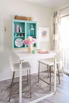 a dining room table with two chairs and a vase filled with flowers