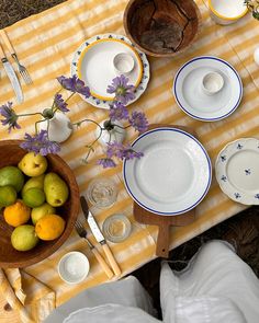 the table is set with plates, bowls and fruit