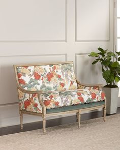 a couch sitting next to a potted plant on top of a rug in front of a white wall