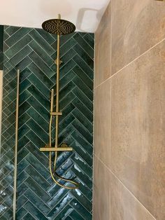 a shower head and hand held shower faucet in a bathroom with green herringbone tile