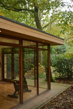 a wooden deck in front of a house with glass walls