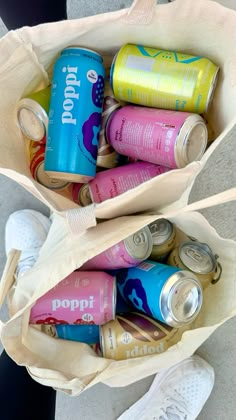 a bag full of soda cans sitting on the ground next to someone's feet