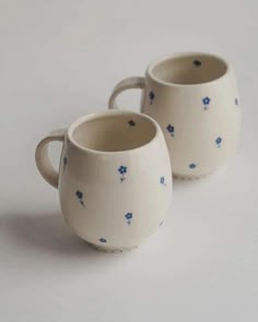 two white cups with blue flowers on them