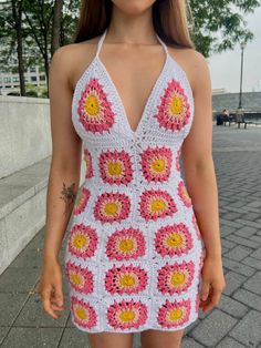 a woman in a crocheted dress standing on the sidewalk