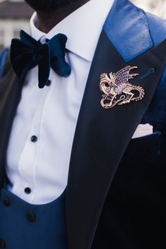 a man in a tuxedo with a dragon brooch on his lapel