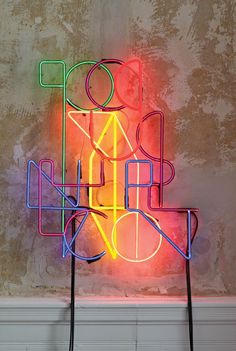 a multicolored neon sign sitting on top of a wooden table next to a wall