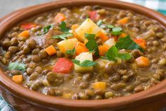 a close up of a bowl of food with peas and carrots in it on a checkered table cloth