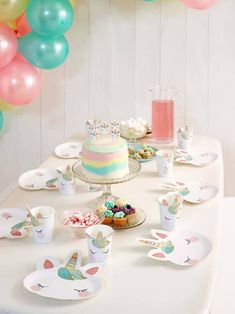 a table topped with cake and cupcakes covered in frosting next to balloons