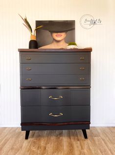 a dresser with two drawers and a painting on the top one has a woman's face painted on it