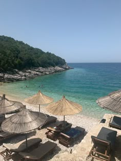 umbrellas and lounge chairs on the beach with clear blue water