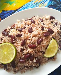 rice, beans and limes are served on a white plate with a colorful table cloth