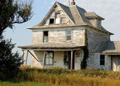 an old run down house with vines growing on the front and side of it's roof