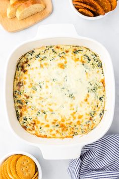 a casserole dish with cheese and crackers on the side