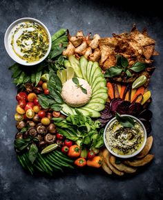 a platter filled with different types of vegetables and dips on top of each other