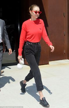 a woman in red sweater and black pants walking on sidewalk with white frisbee