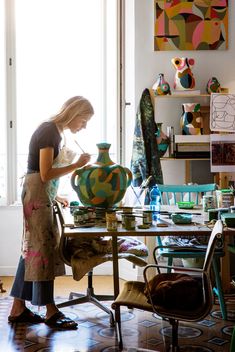 a woman in an art studio working on a vase