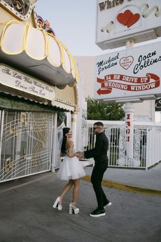 a man standing next to a woman in front of a sign for a wedding venue