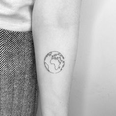 a person with a small tattoo on their arm that has the earth in it's center