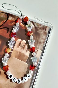 a bracelet with beads that read red is on the front cover of a magazine or brochure