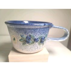 a blue and white cup sitting on top of a wooden block