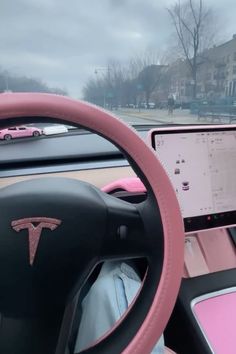 a pink steering wheel with a laptop on the dashboard