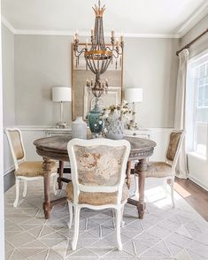 a dining room table with chairs and a chandelier hanging from the ceiling above it