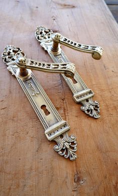 two ornate brass handles on a wooden table