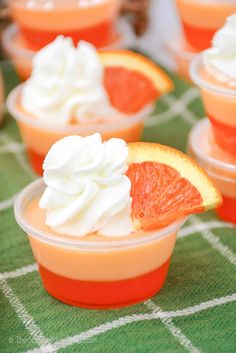 orange dessert cups with whipped cream and grapefruit toppings on green tablecloth