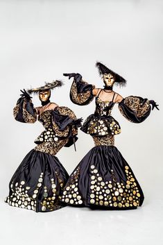 two women dressed in black and gold costumes