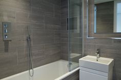 a bathroom with a sink, toilet and bathtub next to a shower head mounted on the wall