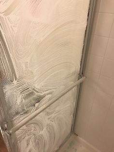 a bathroom with a glass shower door and tile flooring on the wall behind it