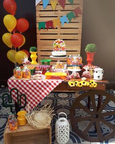 a table topped with lots of food next to a wooden cart filled with cakes and balloons