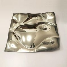 a metal object on a white surface that looks like it has been made out of aluminum