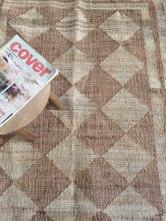 a magazine sitting on top of a wooden table next to a chair and ottoman cover