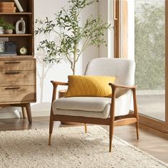 a living room scene with focus on the arm chair and wooden bookcase that has books on it