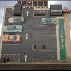 a large mural on the side of a building with cars parked in front of it