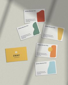 four business cards with different colors and shapes sitting on top of a white countertop