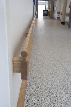 a long hallway with white walls and wooden railings on both sides, leading to an office building