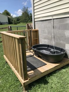 an outdoor hot tub sitting on top of a wooden deck next to a building and grass