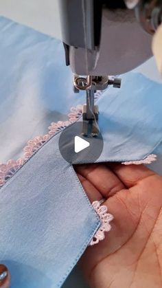 someone is using a sewing machine to sew something on the blue fabric with pink lace