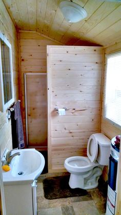 a bathroom with a toilet, sink and shower stall in the corner next to a window