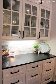 a kitchen with white cabinets and black counter tops