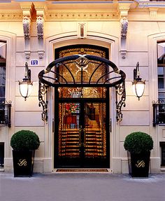 an entrance to a hotel with two large planters and lights on either side of the door