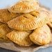 a pile of fried pastries sitting on top of a wooden cutting board next to a knife