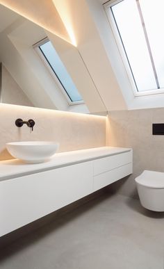 a white bathroom with a skylight in the ceiling and a bowl sink on the counter